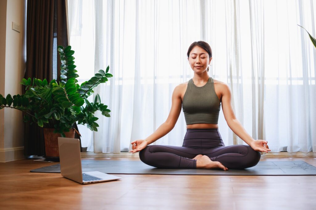 Asian woman yoga teacher filming yoga online class